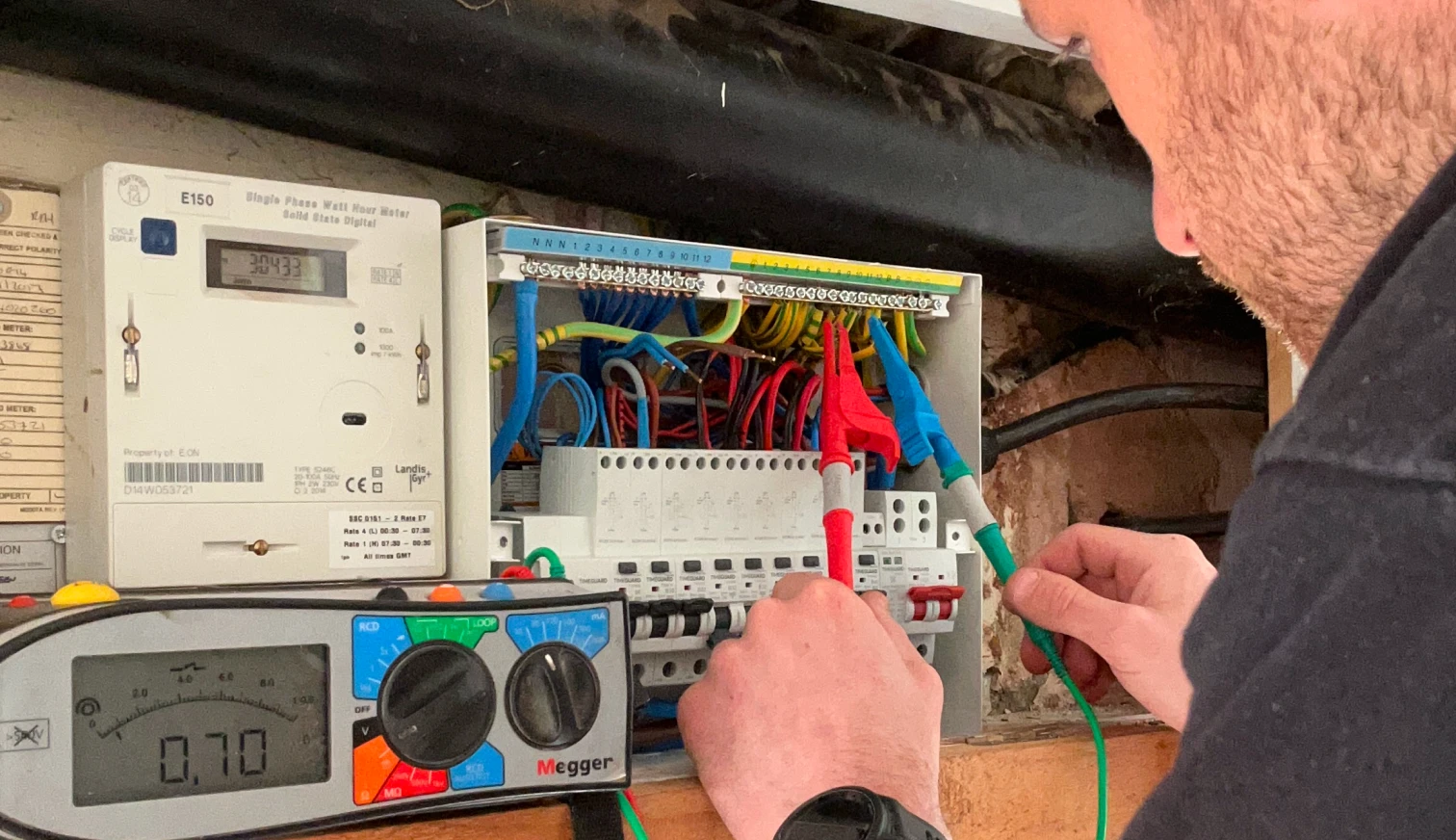 Electrician testing a consumer unit with a Megger multifunction tester during fault finding