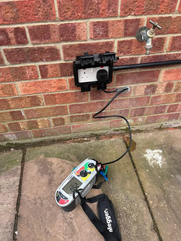 External weatherproof socket on a brick wall being tested with a Megger MFT
