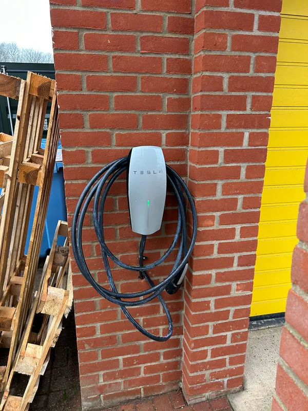 Tesla wall connector with coiled cable mounted on a brick pillar