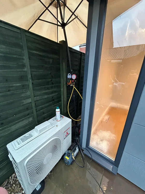 Mitsubishi split air conditioning condenser being commissioned outside a garden room