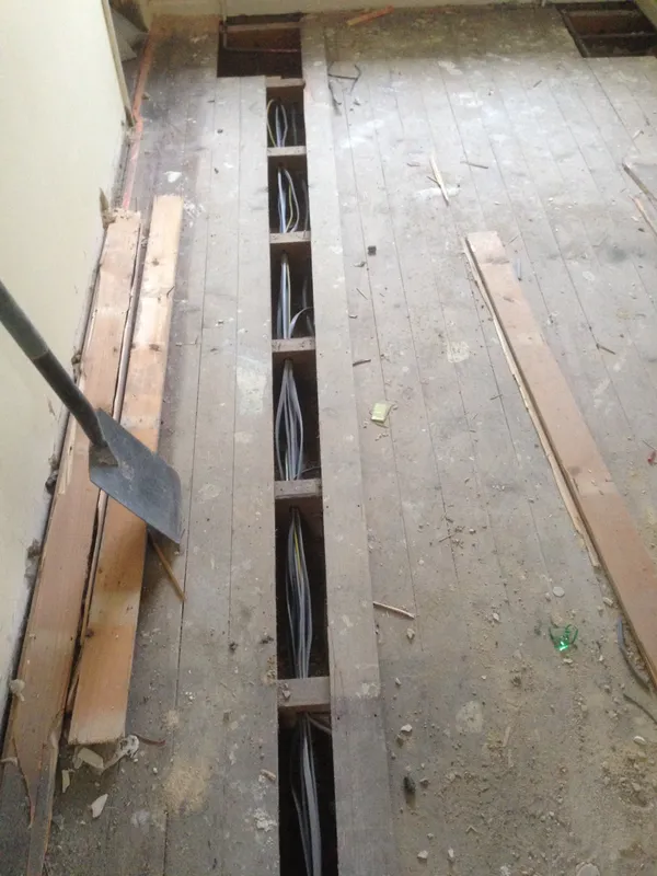 New cabling run beneath lifted floorboards during a rewire