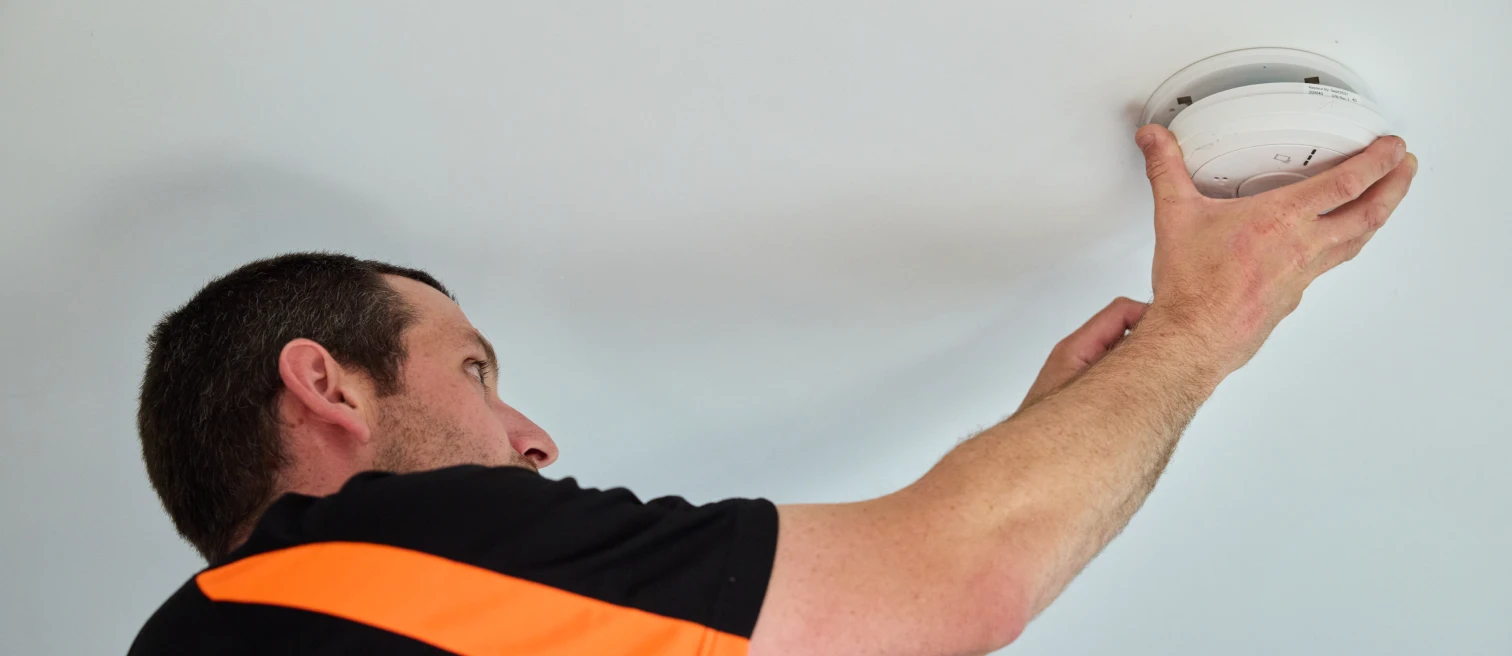 Hethersett Electrical engineer fitting a mains-powered smoke alarm to a ceiling during a rewire